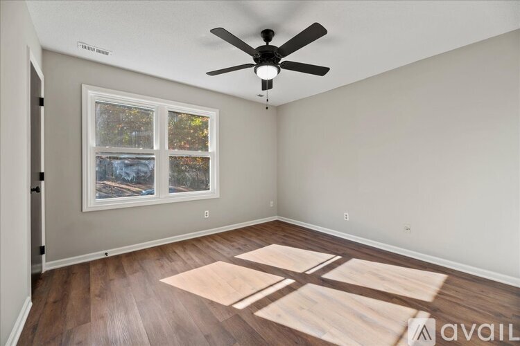 A room with a ceiling fan and a window with a view of trees.