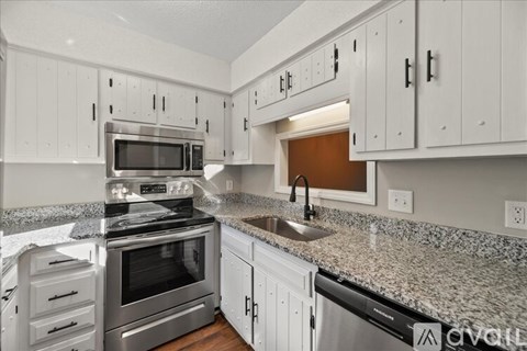 A kitchen with white cabinets and granite countertops.