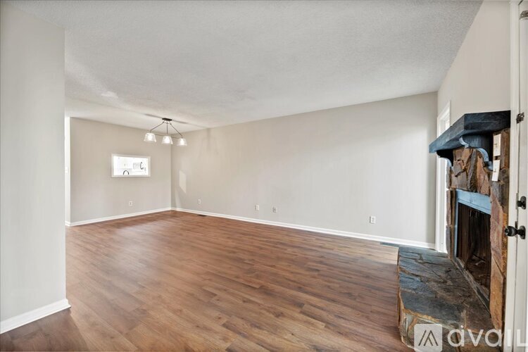 A spacious living room with wooden flooring and a fireplace.
