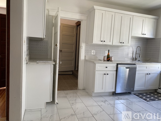 A kitchen with white cabinets and a refrigerator.