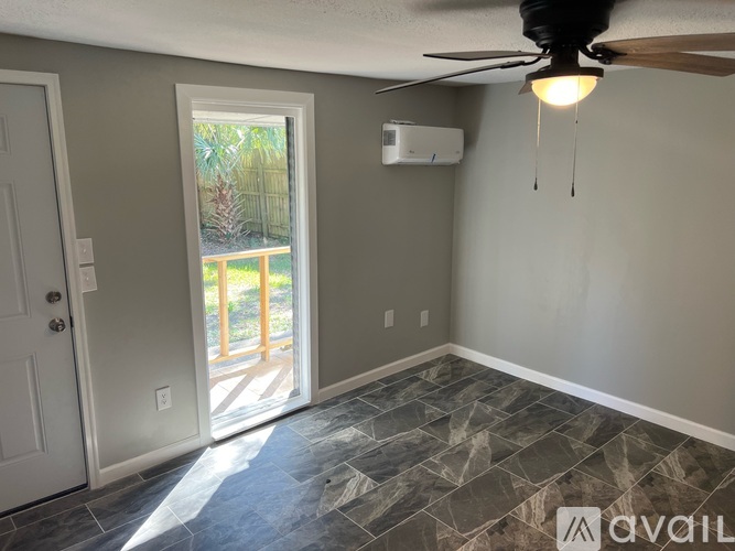 A room with a ceiling fan and a door leading to a balcony.