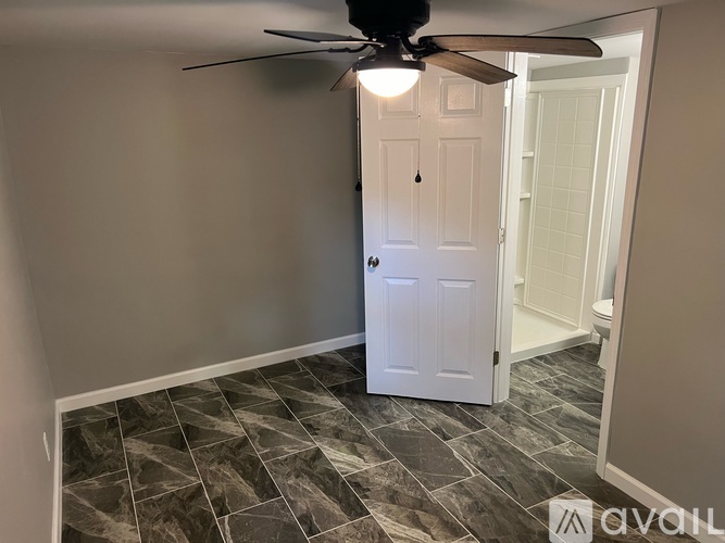 A room with a ceiling fan and a door.