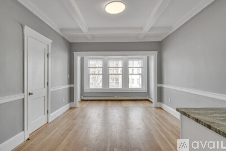 A room with a large window and wooden floors.