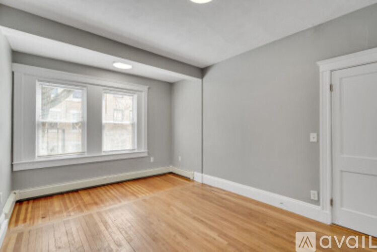 A room with wooden flooring and a window with a view of buildings outside.