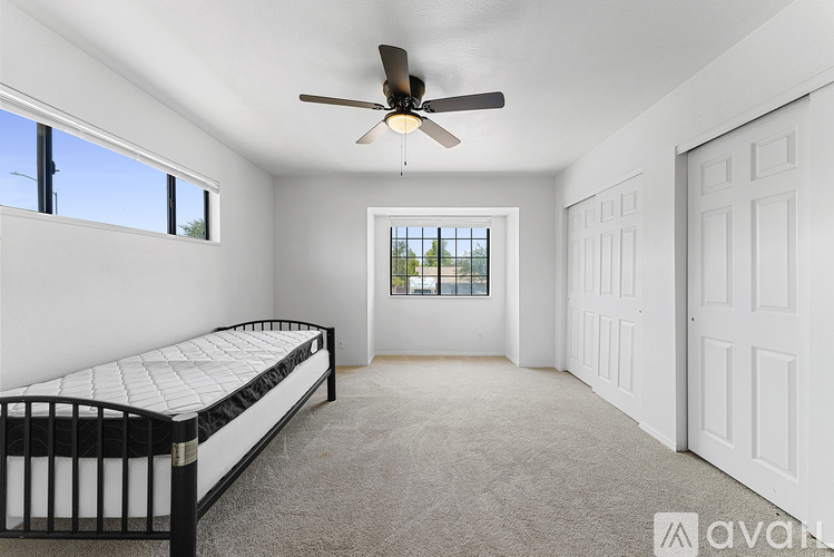 A bedroom with a bed, a ceiling fan, and a window with a view.