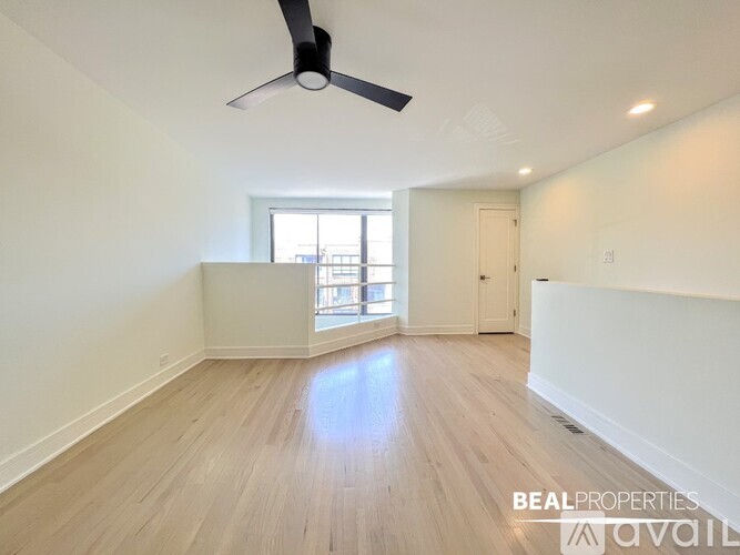 A spacious room with a fan and wooden flooring.