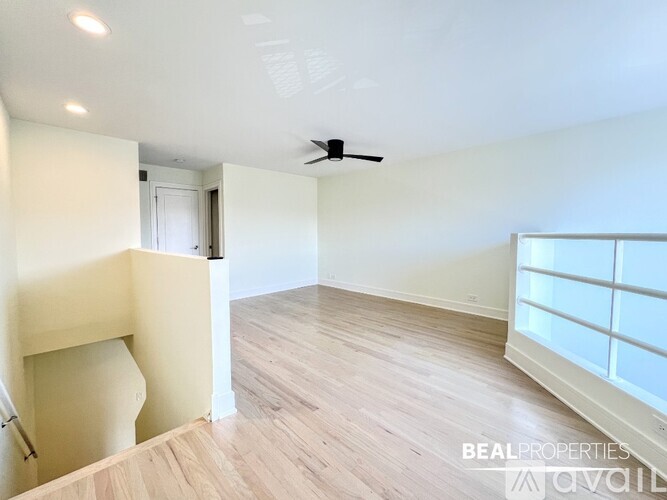 A spacious room with a ceiling fan and wooden flooring.