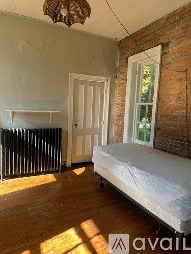 A room with a bed, a radiator, and a window.