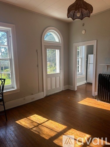 A room with a wooden floor and a window with a view of trees.