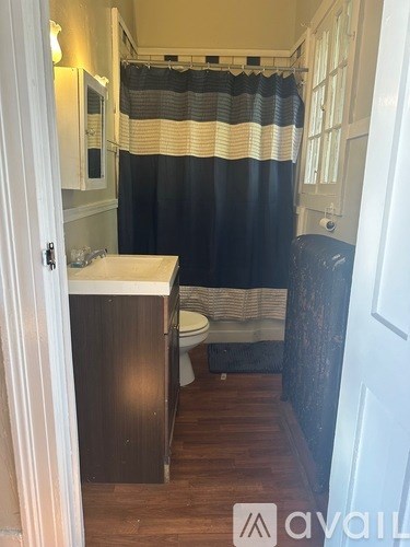 A bathroom with a toilet, sink, and shower curtain.