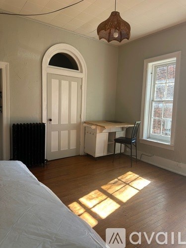 A room with a bed, desk, chair, and window.