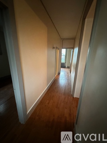 A long hallway with wood floors and white walls.