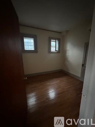 A room with wooden floors and two windows.