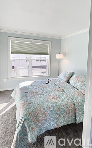 A bedroom with a bed and a window with blinds.