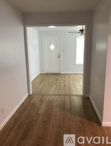 A hallway with wood flooring and a white door.