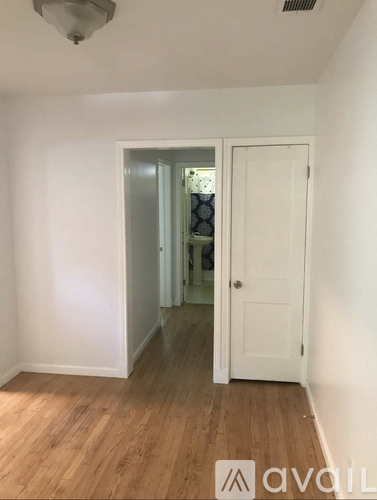 A room with a white door and a wooden floor.
