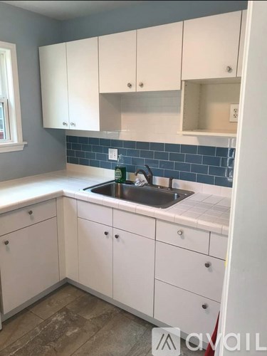 A kitchen with white cabinets and a blue tile backsplash.