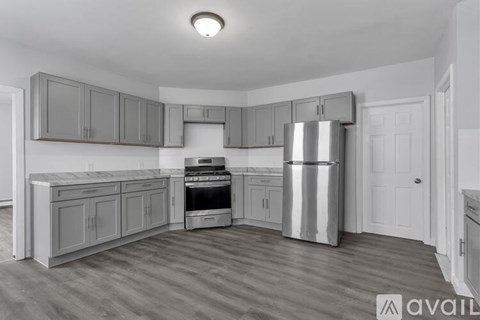 A kitchen with grey cabinets and a stainless steel fridge.
