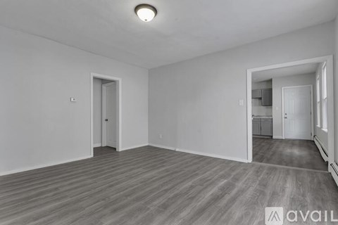 A spacious room with wooden flooring and two doors.