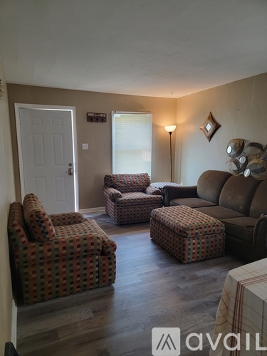 A living room with a couch, chair, ottoman, and lamp.