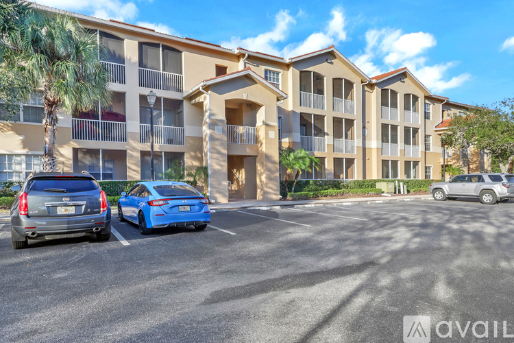 A parking lot in front of a multi-story apartment building with cars parked.