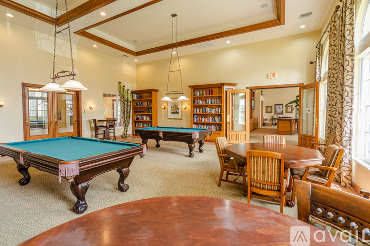 A room with a pool table, chairs, and bookshelves.