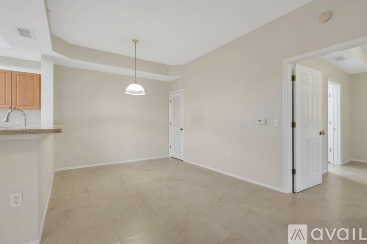 A spacious room with a light hanging from the ceiling and a cabinet on the left side.