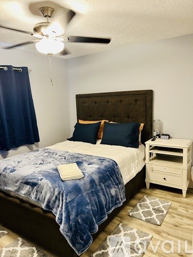 A bedroom with a floral bedspread and a ceiling fan.