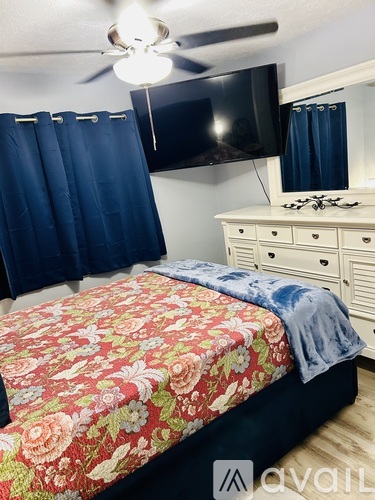 A bedroom with a floral bedspread and a white dresser.