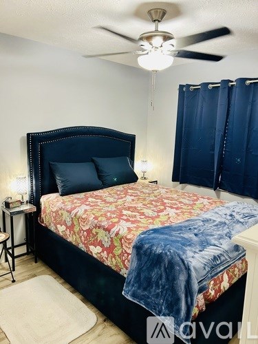 A bedroom with a floral bedspread and a television mounted on the wall.