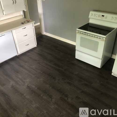A white oven and dishwasher in a kitchen with dark wood flooring.