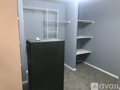 A storage room with a black cabinet and white shelves.