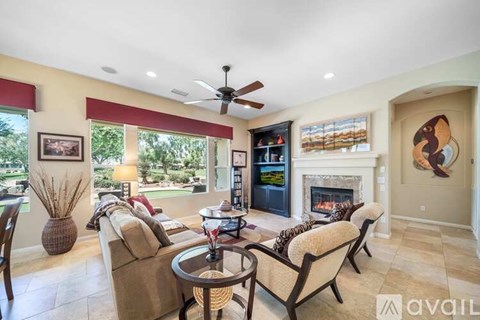 A living room with a fireplace and a ceiling fan.