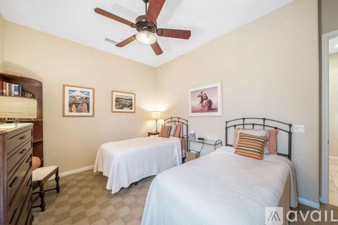 A bedroom with two beds and a ceiling fan.