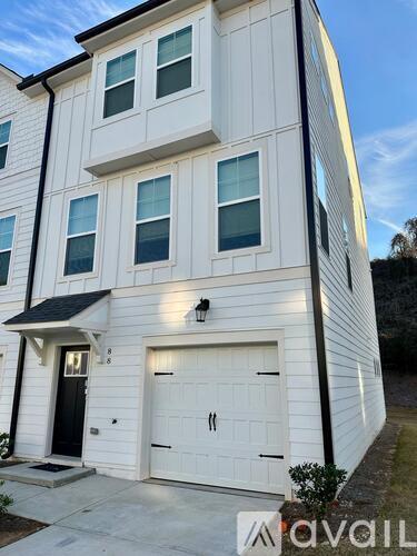 A white two-story house with a black door and windows.