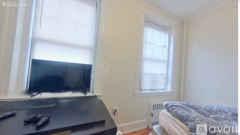 A room with a bed, a desk with a computer, and a window with blinds.