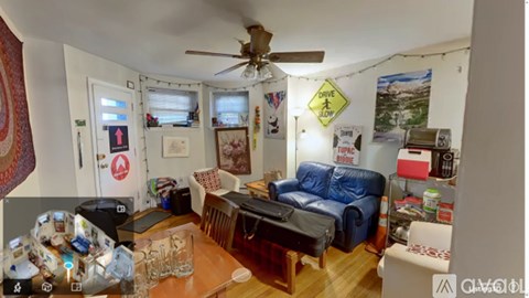 A living room with a blue couch and a ceiling fan.