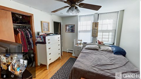 A bedroom with a bed, dresser, and a ceiling fan.