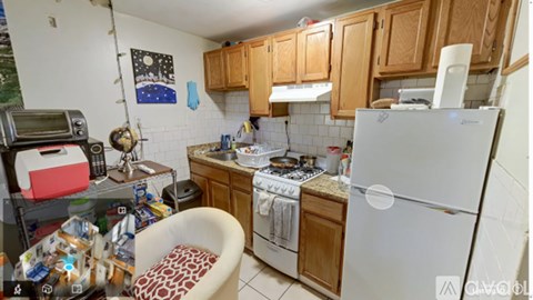 A kitchen with a white refrigerator, wooden cabinets, and a white stove top.