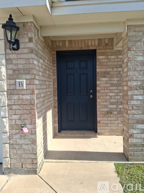A black door is set in a brick wall with a letter B above it.