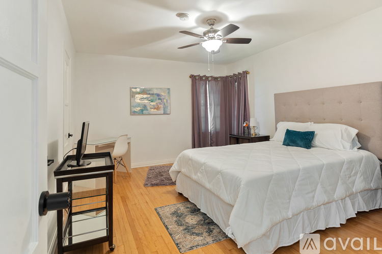 A bedroom with a bed, a chair, a desk, and a ceiling fan.