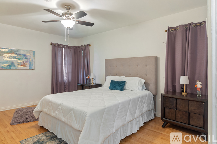 A bedroom with a large bed and a ceiling fan.