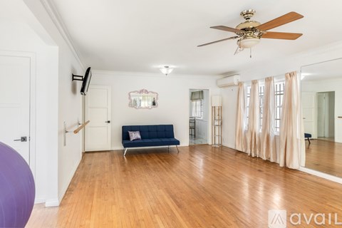 A spacious living room with a blue sofa and wooden flooring.