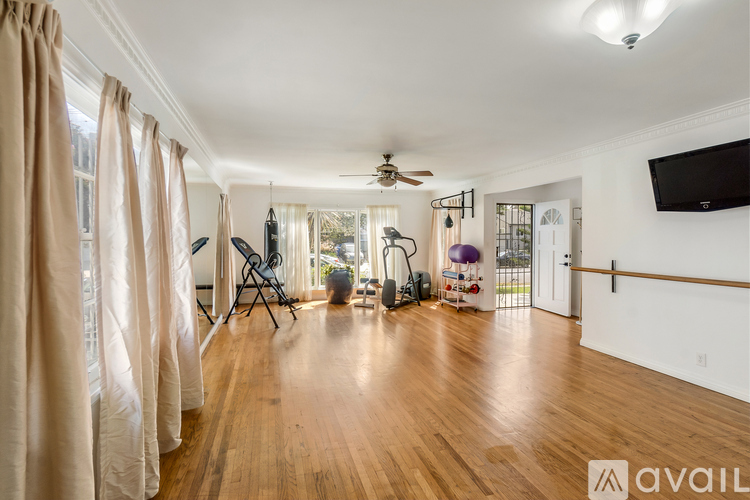 A spacious room with wooden floors and a ballet barre on the wall.