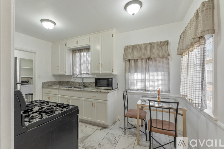 A kitchen with a black stove top oven and a dining table with chairs.