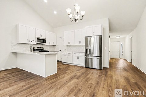 A kitchen with white cabinets and a wooden floor.