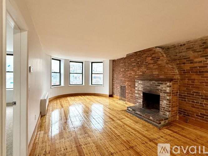 A room with a brick fireplace and wooden floors.