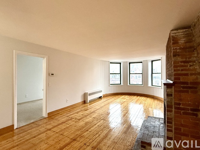 A room with wooden floors and a brick wall.