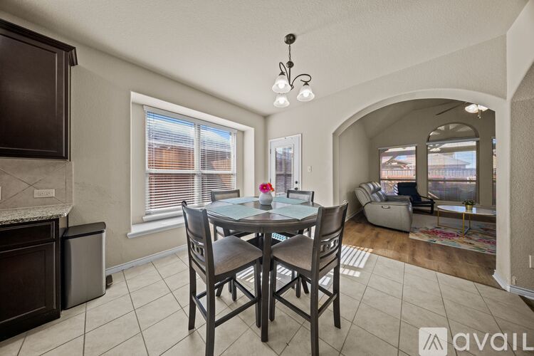 A dining room with a table set for two and a couch in the background.