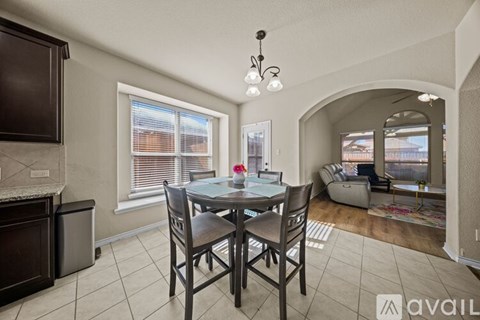 A dining room with a table set for two and a couch in the background.